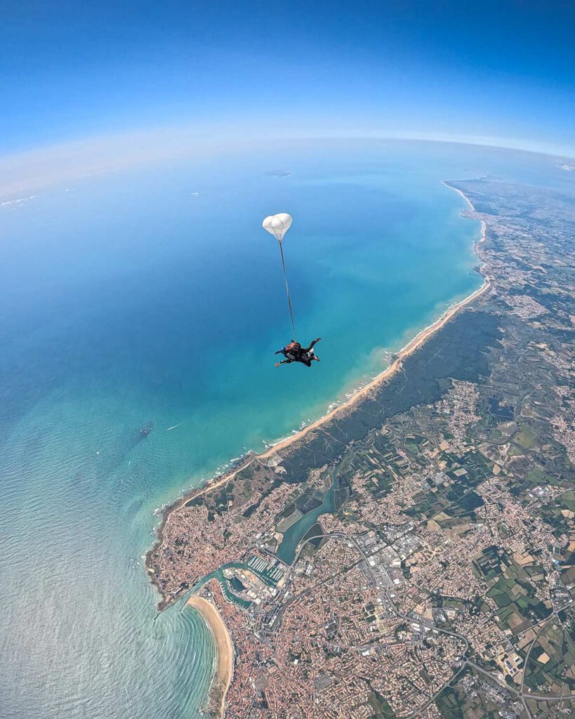 Tandem HALO à 7 700 m sous oxygène survolant la côte vendéenne, parachute extracteur (RSE) déployé, vue sur Les Sables-d’Olonne.